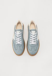 Baskets en jean bleu clair avec des lacets blancs, un col crème et une semelle en caoutchouc marron. Présente un design d'accent blanc.