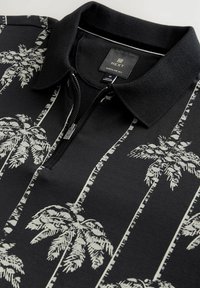 Tricou polo negru cu model alb de palmieri, fermoar parțial și guler texturat negru. Fabricat dintr-un material moale, cu o croială normală.