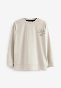 Sweatshirt long à manches longues beige clair avec un col rond, présentant un texte imprimé en marron foncé et des poignets et un ourlet côtelés.