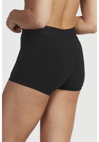 Svarta träningsshorts med en elastisk midja, slät yta och en åtsittande design som täcker den övre låret. Inga synliga logotyper eller mönster.
