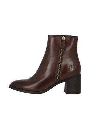Bottine en cuir marron avec un bout arrondi, fermeture éclair sur le côté, talon bloc et détail de logo embossé sur le côté extérieur. Texture lisse.