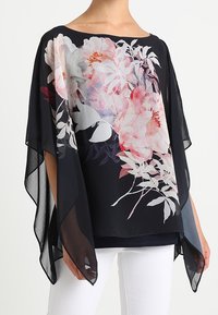 Svart blommig kimono-top i genomskinligt tyg, med stora rosa och vita blommor, flödande ärmar och en lös, avslappnad passform.