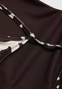 Brun badeshort med camouflage-mønster og glat tekstur, prydet med kontrasterende hvide detaljer og syede kanter. Tydelig låsning synlig.