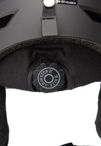 Svart hjälminredning med en texturerad tygfoder, justerbar storleksdial och rem med ett säkert fästsystem.