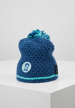 Blue knitted beanie with a pom-pom, featuring a light blue band and a circular logo patch. Textured, soft yarn with a relaxed fit.