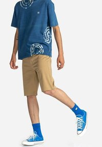 Blauwe tie-dye katoen t-shirt, beige shorts, blauwe sokken en blauwe canvas sneakers. Heeft witte accenten en een ontspannen pasvorm voor comfort.