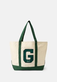 Saco de tela em creme com alças e base verdes; apresenta um grande logótipo 'GAP' bordado em verde na frente.