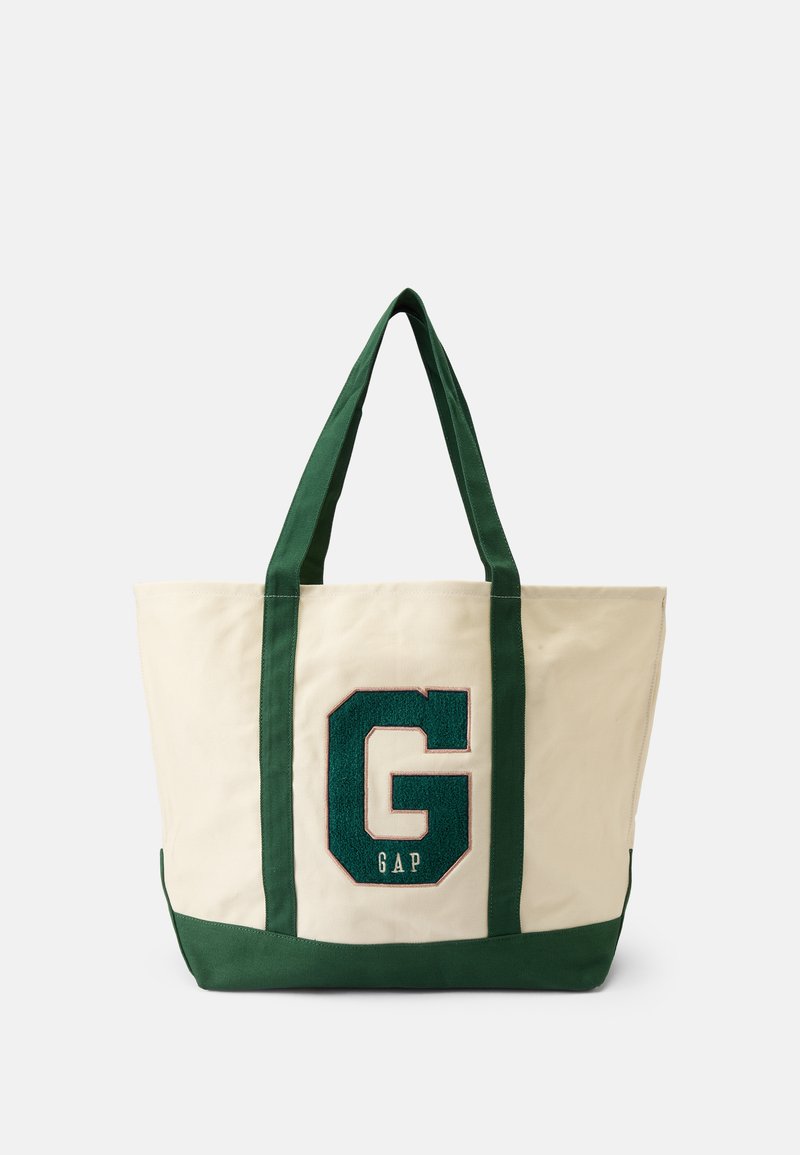 Sac en toile crème avec des anses et une base vertes ; présente un grand logo 'GAP' en vert brodé sur le devant.