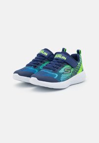 Baskets de sport bleu marine avec empeigne en mesh, ornées de motifs verts et bleus, semelle en caoutchouc blanche et embout renforcé ; sangle ajustable pour un bon maintien.