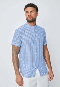 Chemise à manches courtes avec des rayures verticales bleues et blanches, dotée d'un col mandarin et d'une coupe décontractée. Fabriquée en tissu léger.