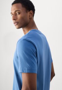 Blauwe T-shirt met korte mouwen en een ronde hals, van gladde katoenstof, met een relaxte pasvorm en subtiele stikseldetails op de mouwen.
