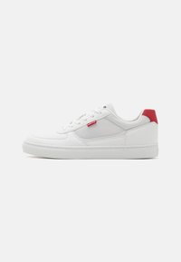 Valkoinen sneakers-kengät, joissa on verkko- ja nahkamateriaali, pyöreä kärki, punainen kantapään aksentti ja valkoinen kumipohja. Varustettu nauhakiinnityksellä ja brändätyllä tarralla.