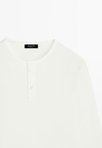 Hvid skjorte med lange ærmer, rund halsudskæring og tre-knaps lukning, med en sort "Massimo Dutti" label inde i kraven.