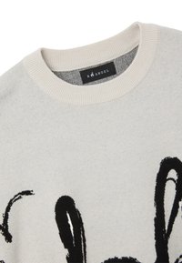 Suéter gris claro con cuello redondo, hecho de tela suave, que presenta un audaz diseño abstracto negro en la parte frontal. Etiqueta de la marca visible.