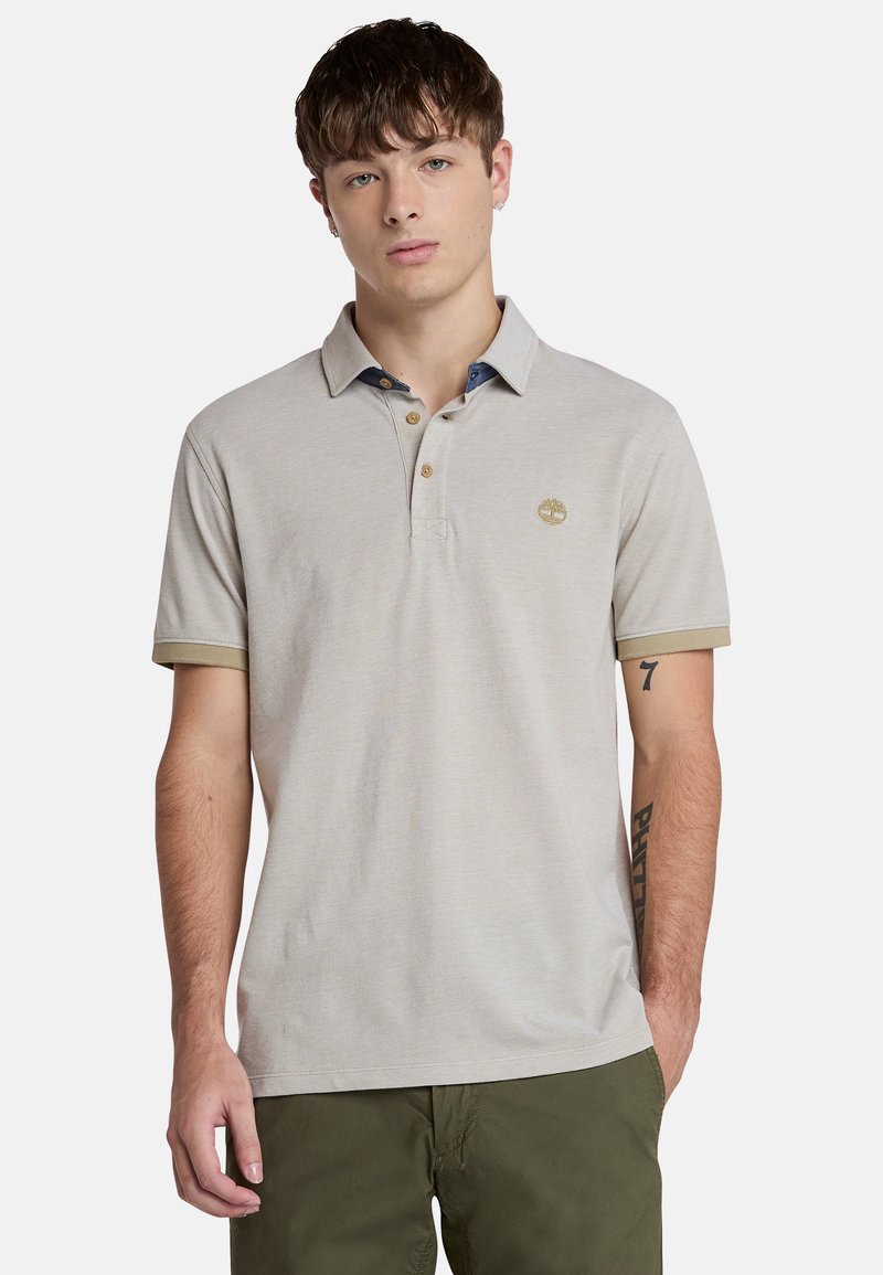 Ljusgrå pikétröja med klassisk krage, som har tre knappar och en kontrasterande blå innerkrage. Inkluderar subtila logotyp- och manschettaccent.