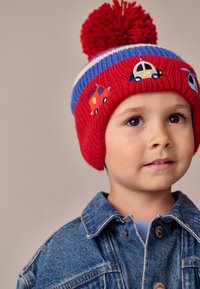 Rød strikket hue med blå stribe og dusk, med broderede biler og en helikopter. Varmt, fleksibelt materiale med ribbet tekstur.