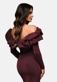 Burgundy axelklänning med volangärmar, figursydd silhuett, texturerad tyg, och långa ärmar som visar en subtil lyster.