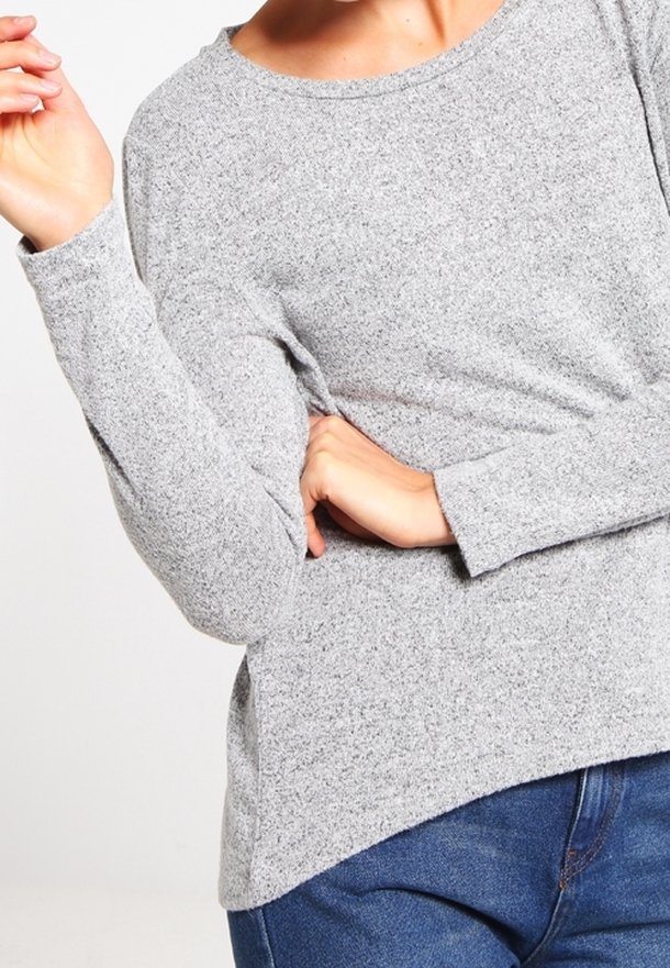 Haut en tricot gris à manches longues avec col rond, coupe décontractée et tissu texturé. Assorti à un jean en denim bleu.