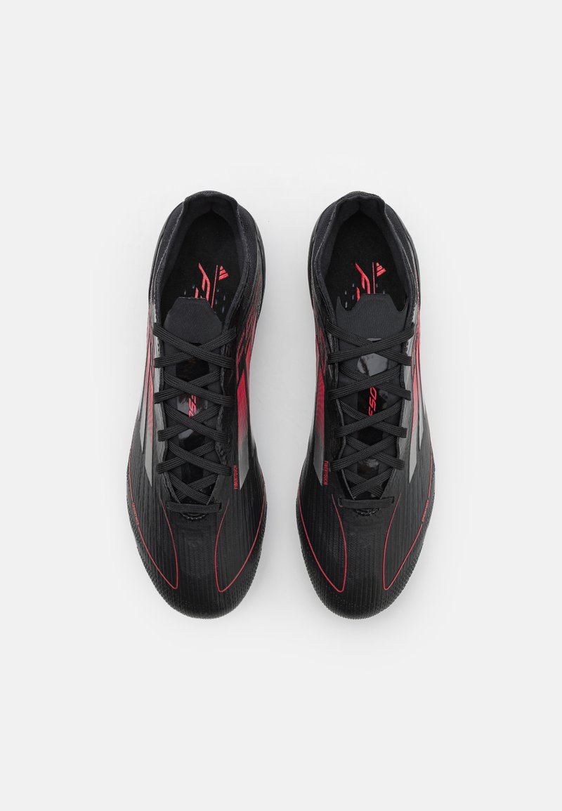 Zapatillas deportivas negras con acentos rojos, con un diseño elegante, superficie texturizada y cordones. Marca visible en el lateral.