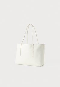 Witte rechthoekige tote bag met subtiel geometrisch patroon en dunne schouderbanden, weergegeven tegen een effen lichte achtergrond.