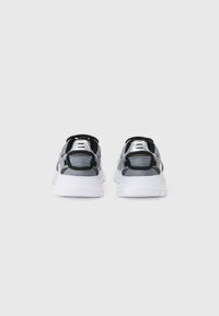 Baskets de sport avec une tige en mesh noire et grise, dotées d'une semelle blanche, d'accents textiles et d'un col rembourré pour le confort.
