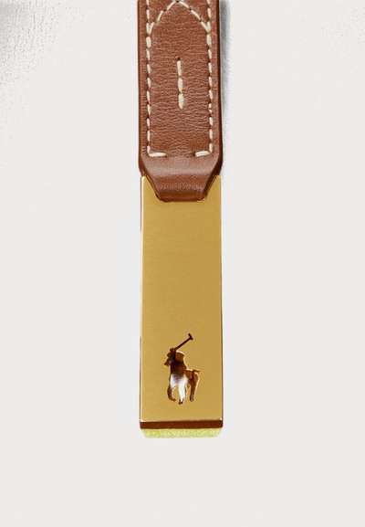 Zelta taisnstūra birka ar brūnu ādas siksnu. Birka piedāvā izgriezumu ar polo spēlētāja siluetu, izceļot tās pulēto tekstūru.