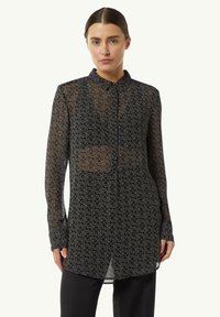 Black sheer shirt with long sleeves, collared neckline, and geometric patterned detail. Features button closure and a loose fit design.