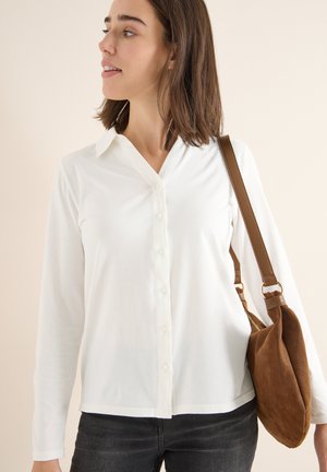 Weißes Langarm-Hemd mit Knopfleiste und Kragen, kombiniert mit einer Schultertasche aus braunem Wildleder. Einfaches Design mit glatter Textur.