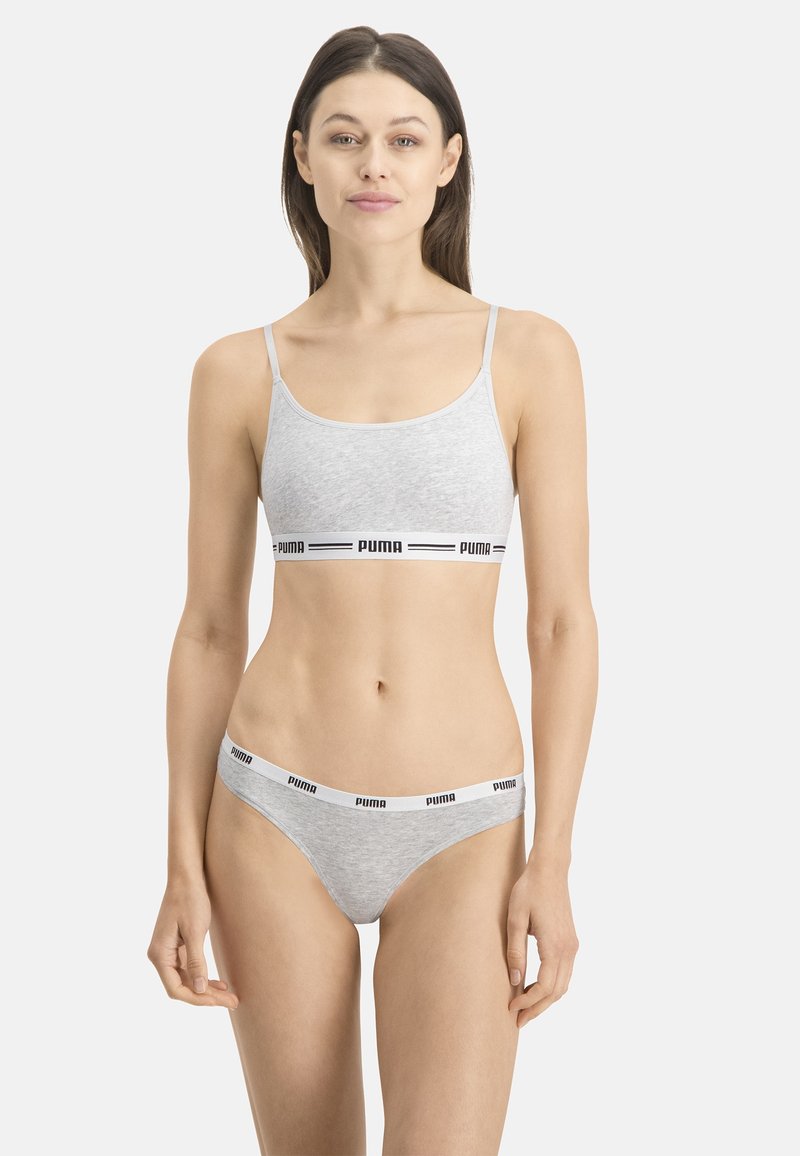 Bralette en coton gris avec des bretelles fines et un bandeau noir portant le logo PUMA ; string assorti gris avec un bandeau similaire. Tissu doux et extensible.