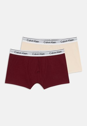 Deux paires de boxers : une maroon et une beige. Chacune présente une ceinture douce avec un logo "Calvin Klein" noir. En matériau coton.