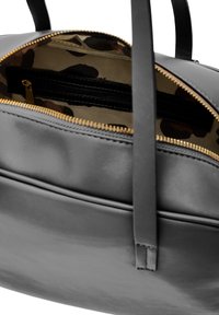 Czarna skórzana torba z złotym zamkiem. Wnętrze wykończone beżową podszewką z kamuflażowym wzorem i bezpieczną kieszenią na zamek.