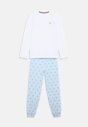 Camiseta blanca de manga larga con cuello de rayas rojas y azul marino, combinada con pantalones azul claro a rayas con un pequeño patrón en azul marino.