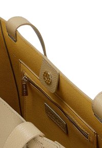 Beżowa skórzana torebka od wewnątrz z musztardowym podszyciem, kieszonką na zamek błyskawiczny oraz dekoracyjnym zapięciem na zatrzask o kształcie fasetki.