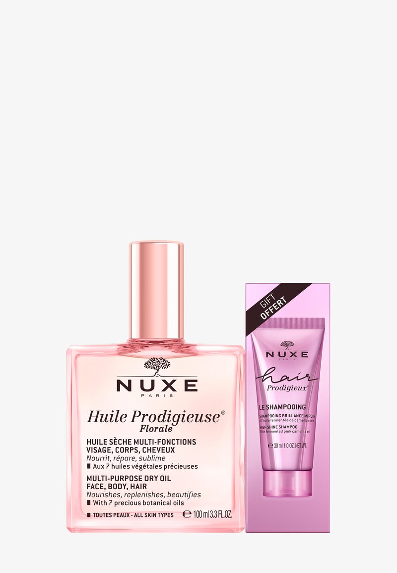 NUXE Huile Prodigieuse® Floral: heldere glazen fles, roze vloeistof, zilveren dop. Cadeaubox met roze buis, productnaam in zwart, en zwarte details.