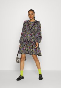 Vestido com estampa floral, mangas longas, base preta e flores multicoloridas. Apresenta um decote em V e cintura franzida.