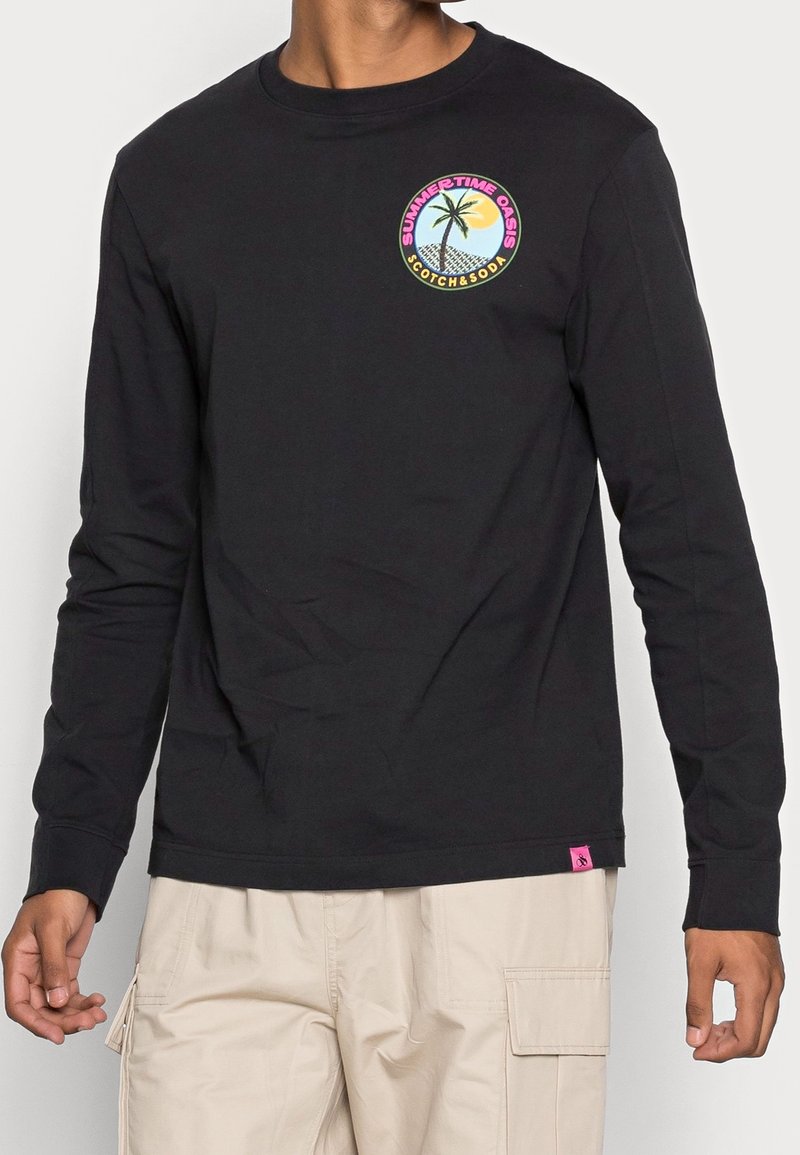 Schwarzes Langarmshirt aus Baumwolle mit grafischem Rundmotiv eines Palmenbaums und einer Sonne sowie dem Text "SUMMERTIME OASIS." Pinker Logosticker am Saum.
