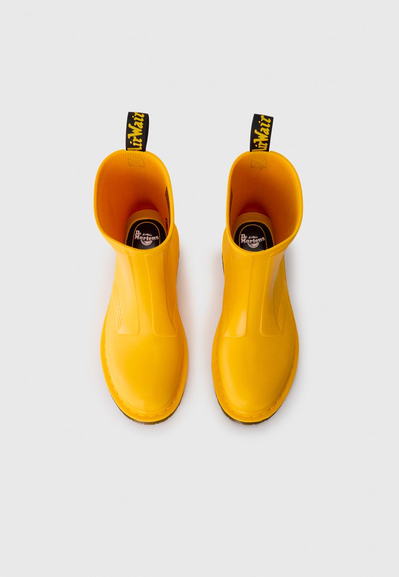 Yellow rubber ankle rain boots with a smooth texture, rounded toe, and pull tab featuring contrasting black text. Outsole is textured for traction.