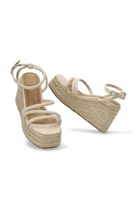 Sandalias de cuña de esparto beige con múltiples tiras finas, plataforma de yute texturizado y un tacón elevado. Detalle de correa ajustable en el tobillo.