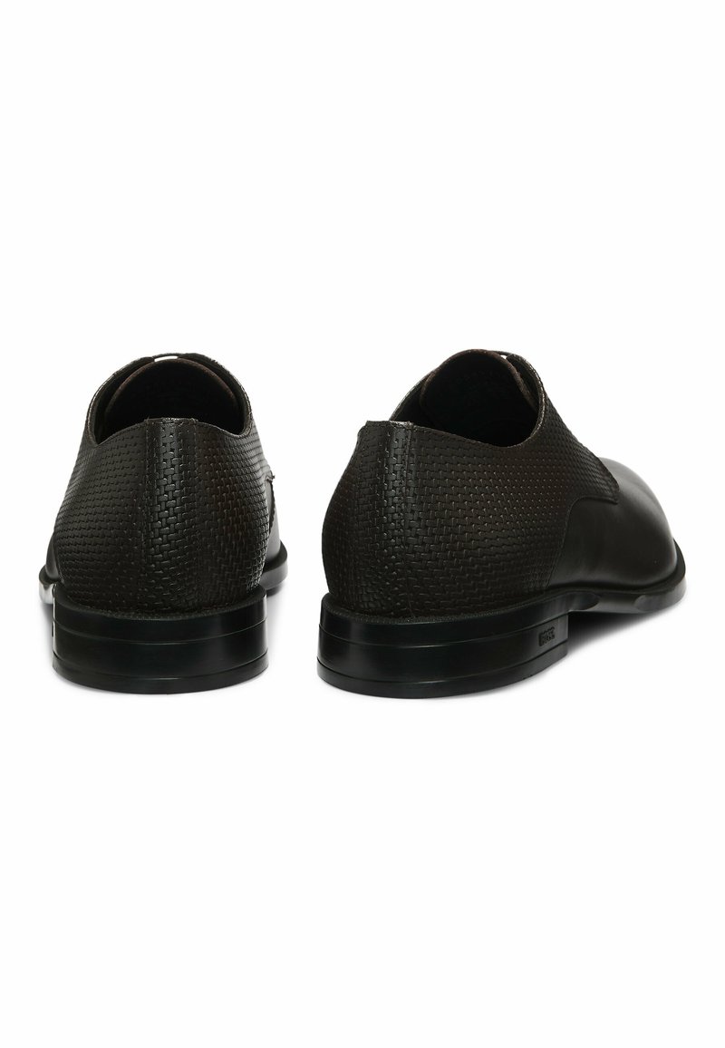 Chaussures en cuir noir avec un talon texturé et une finition lisse, dotées d'un bout arrondi et d'une semelle d'extérieur profilée basse.