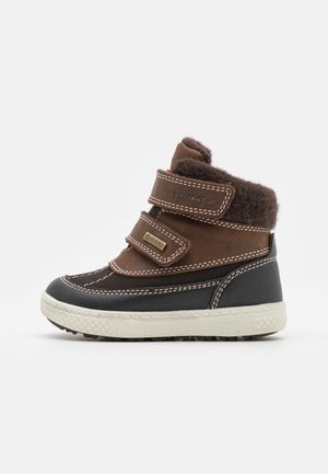 Botte d’hiver enfant marron et noire avec double fermeture Velcro, doublure en polaire et semelle blanche texturée, fabriquée avec un matériau Gore-Tex imperméable.