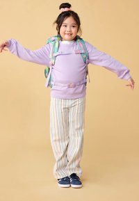 Sweatshirt violet avec un design à plusieurs couches, pantalon rayé multicolore et baskets bleues. Le sac à dos présente un schéma de couleurs pastel et des bretelles ajustables.
