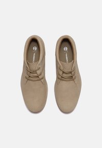 Chaussures en daim beige à lacets avec des bouts ronds, des colliers rembourrés et un design texturé. Comprend des coutures discrètes et une semelle intérieure de marque.