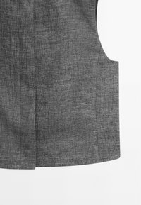Tissu gris avec un motif subtil de lignes noires irrégulières, avec un ourlet droit et une découpe latérale à l’emmanchure.