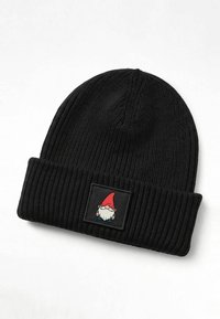 Schwarze gestrickte Mütze mit geripptem Muster und umgeschlagenem Bündchen. Mit einem quadratischen Aufnäher, der einen Gnom mit rotem Hut und weißem Bart zeigt.