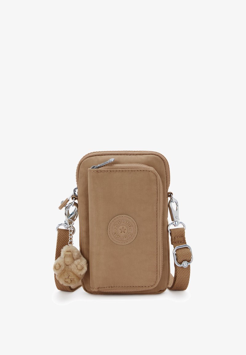 Borsa a tracolla piccola color beige con tasca frontale con cerniera, patch del logo Kipling, tracolla regolabile e un portachiavi a forma di scimmietta in peluche attaccato.