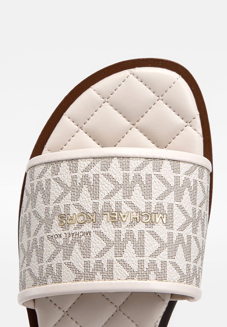 Sandale blanche à glissière avec un dessus matelassé et une sangle à motif ornée d'un logo doré. Matériau lisse semblable à du cuir avec une semelle extérieure marron.