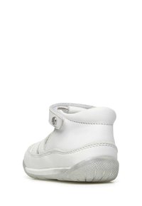 Witte leren schoen met een klittenbandsluiting, voorzien van een uitgesneden ontwerp, gevoerd kraag en een gestructureerde rubberen zool voor grip.
