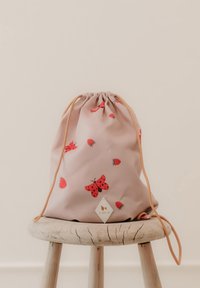 Lyserød rygsæk med snøre, dekoreret med røde sommerfugle- og jordbærmotiver, lavet af glat materiale med tan snor og et trekantet logomærke.