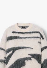 Kötött pulóver, kerek nyakkivágással, fehér alapon fekete absztrakt mintákkal, puha, texturált anyagból készült, és címke található a nyakrésznél.