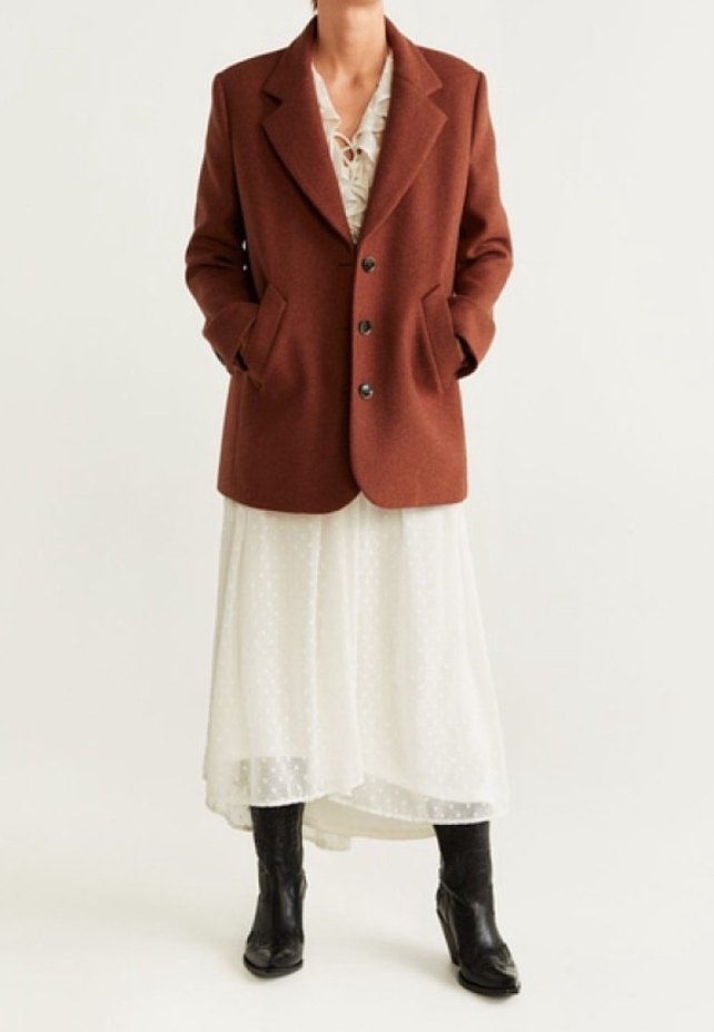 Blazer en mélange de laine marron avec un col cranté et trois boutons, porté sur une robe blanche à pois fluide et des bottines noires.